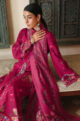 Woman wearing a vibrant pink traditional outfit with intricate patterns in a decorative setting.