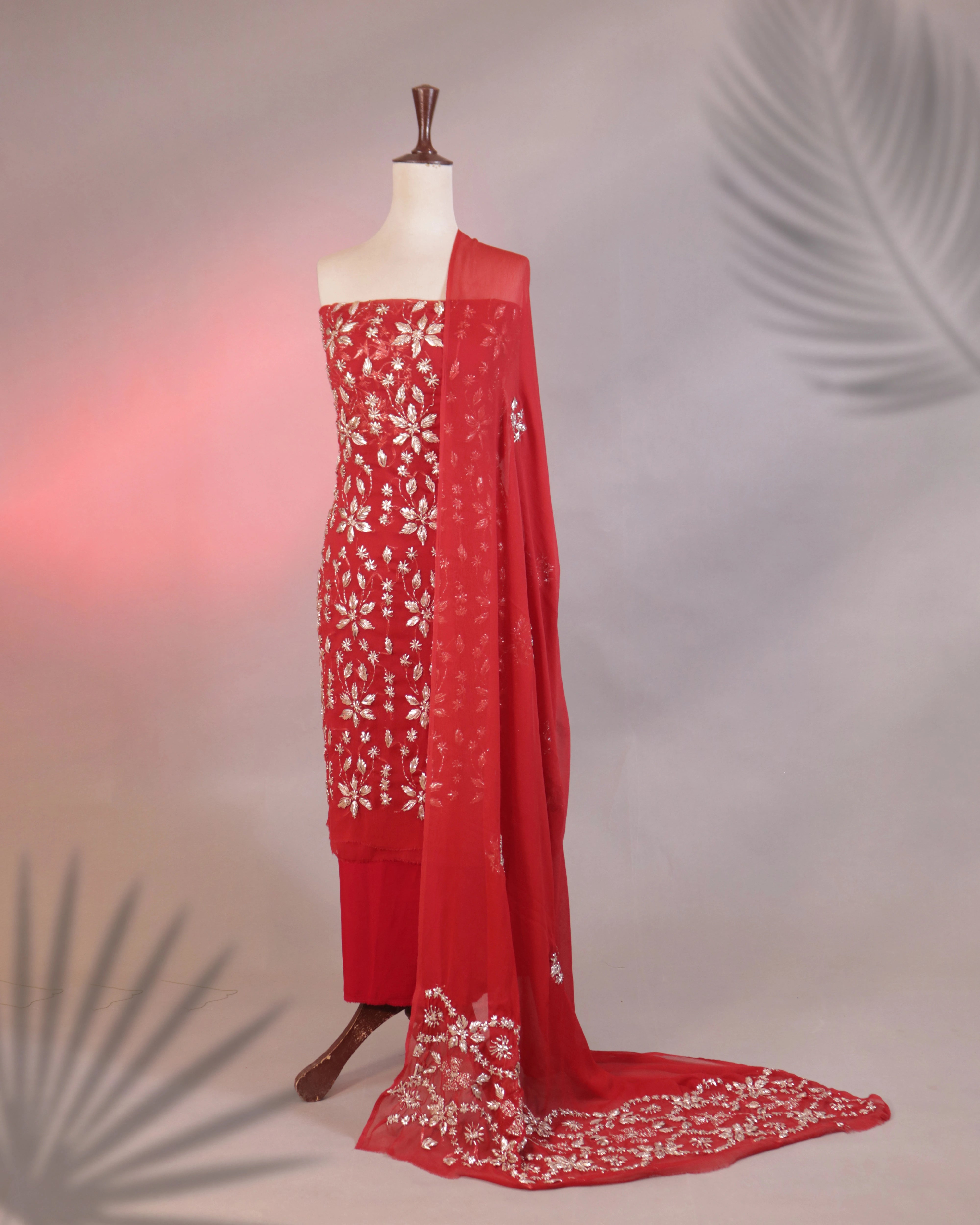Red saree with white floral embroidery on a mannequin against a neutral background
