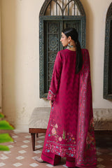 Woman in a red traditional outfit standing in a room with decorative walls and a patterned floor.