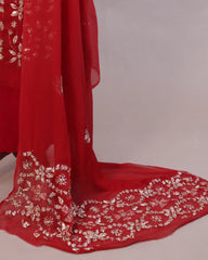 Red fabric with intricate white embroidery on a neutral background