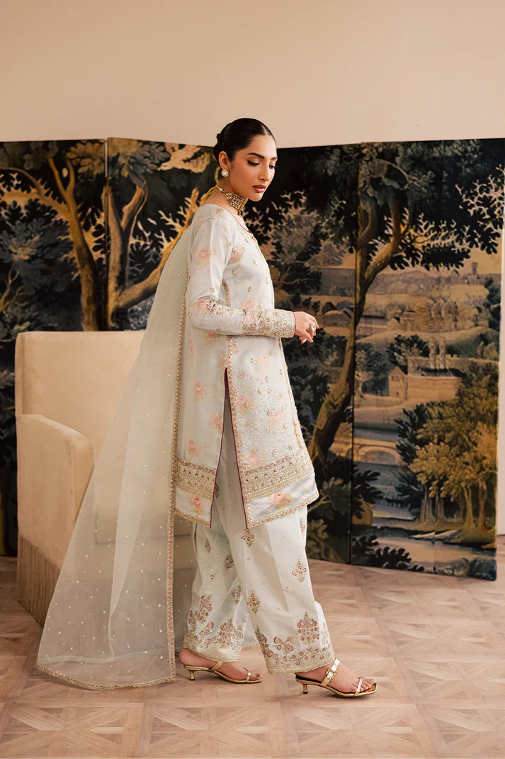 Woman in a traditional outfit standing in front of a decorative wall with a landscape painting.